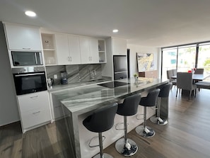 Eine moderne Küche mit einer zentralen Kochinsel, Barhocker und einem Essbereich mit Tisch und Stühlen.