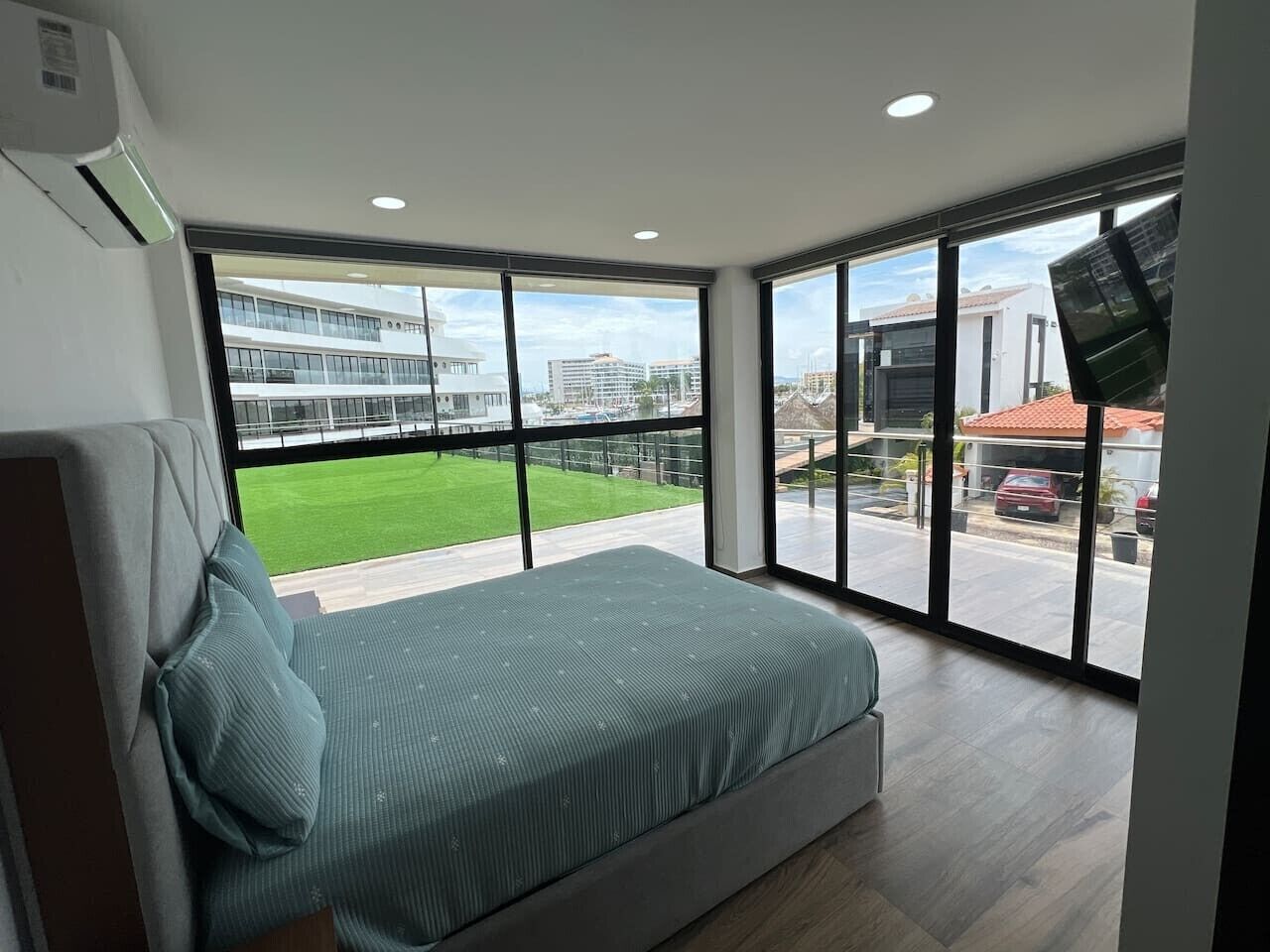 A modern bedroom with a large bed, a view of a building, and a street.