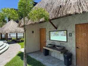 A modern bathroom with a large mirror, two sinks, and a thatched-roof structure. - departamento en isla marina mazatlan (Mazatlan)