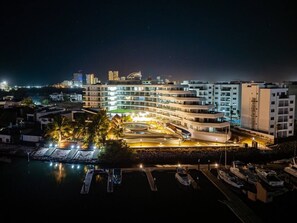A waterfront hotel with multiple buildings, a marina, and a well-lit promenade. - departamento en isla marina mazatlan (Mazatlan)