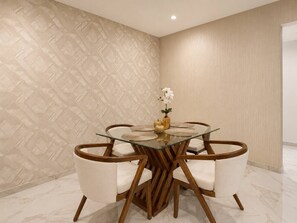 Ein Essbereich mit einem runden Glastisch, Holzstühlen und einer Blumenvase.