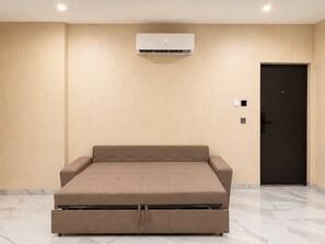 Une pièce comprenant un lit, un appareil de climatisation, une porte et un interrupteur.