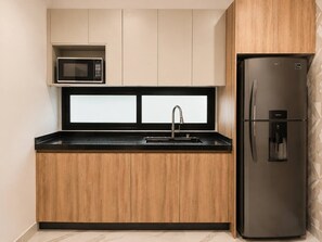 A modern kitchen with a built-in microwave, a stainless steel refrigerator, and a sink with a faucet. - Ubicación ideal | depto. nuevo con 2 recámaras (Mazatlán)