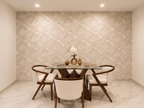 Un espace repas comprenant une table ronde en verre, six chaises rembourrées et un élément décoratif central.