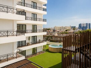 Ein mehrgeschossiges Gebäude mit Balkonen, einem Swimmingpool und Blick auf die Stadtlandschaft.