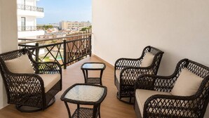 A balcony with wicker furniture, a view of buildings, and a railing.