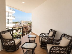 A balcony with wicker furniture, a view of buildings, and a railing.
