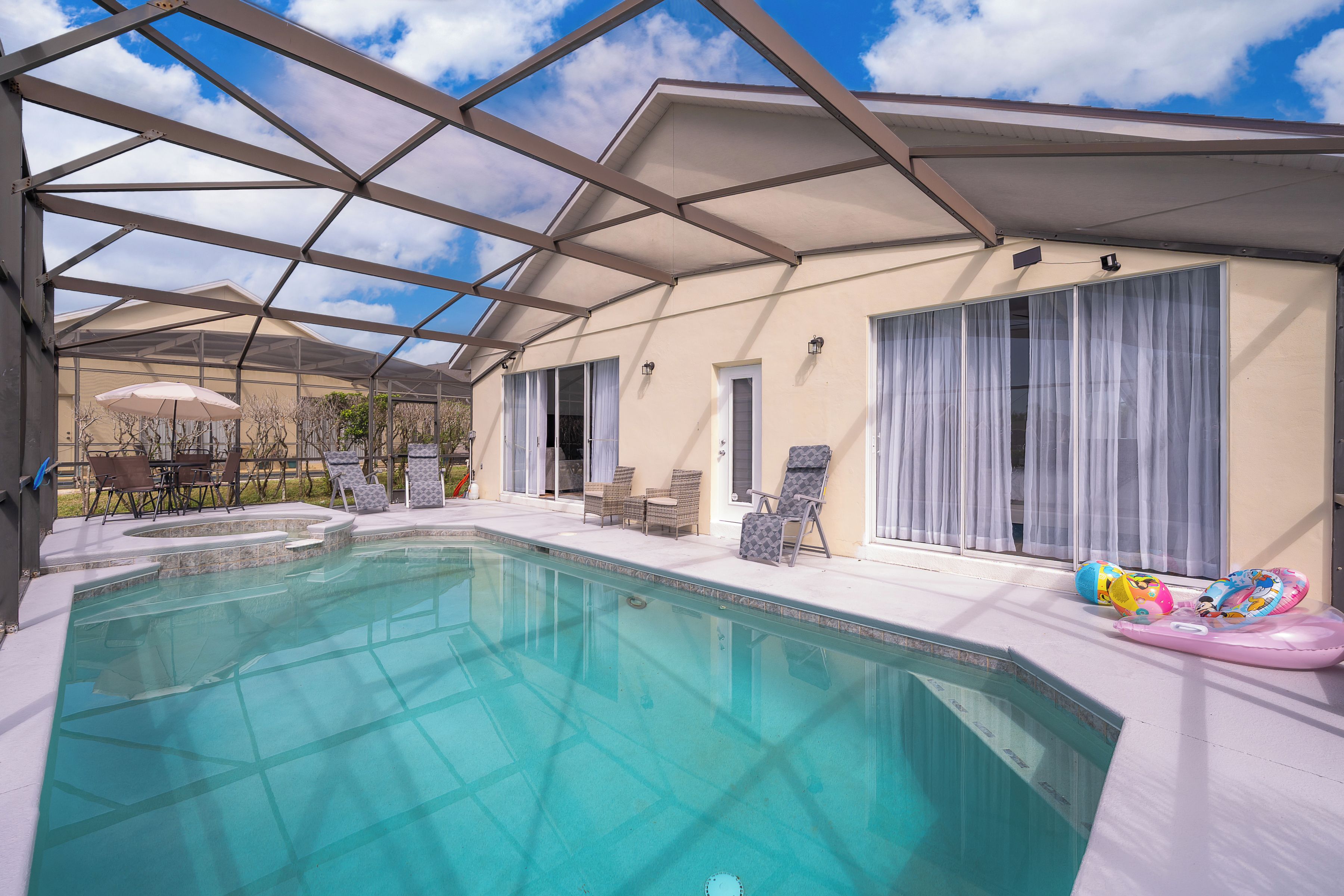 A swimming pool with a glass ceiling, lounge chairs, and a covered patio area.