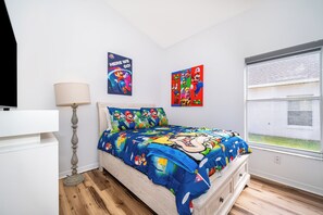 A bedroom with a bed featuring a Super Mario themed duvet, a standing lamp, and two posters on the wall. - 4-Bedroom Pool Home Near Disney | 2 Master Suites | Sleeps 10 (Clermont)
