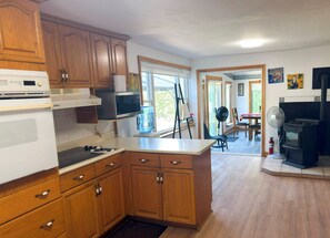 A kitchen with wooden cabinets, a microwave, a water dispenser, and a stove.