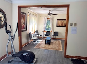 A gym area with exercise equipment, a ceiling fan, and a sign indicating it is for adults only.