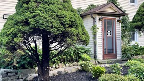Une maison avec un jardin bien entretenu, un mur de soutènement en pierre et une porte ornée d’un autocollant représentant un visage souriant.