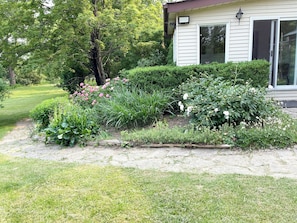 Il s’agit d’une propriété résidentielle dotée d’un jardin bien entretenu, d’un chemin menant à la maison et d’une grande fenêtre située sur le côté droit.