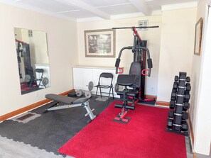 A home gym with a bench press, squat rack, and various weights.