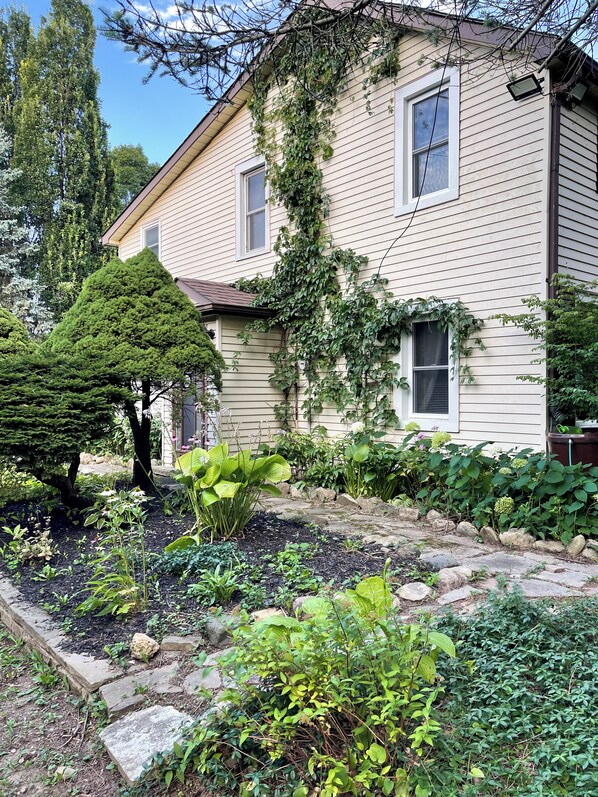 A house with a garden, a well-maintained lawn, and a large tree.