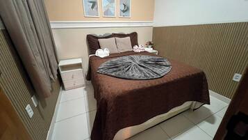 A hotel room with a bed, a nightstand, a lamp, and a window with curtains.