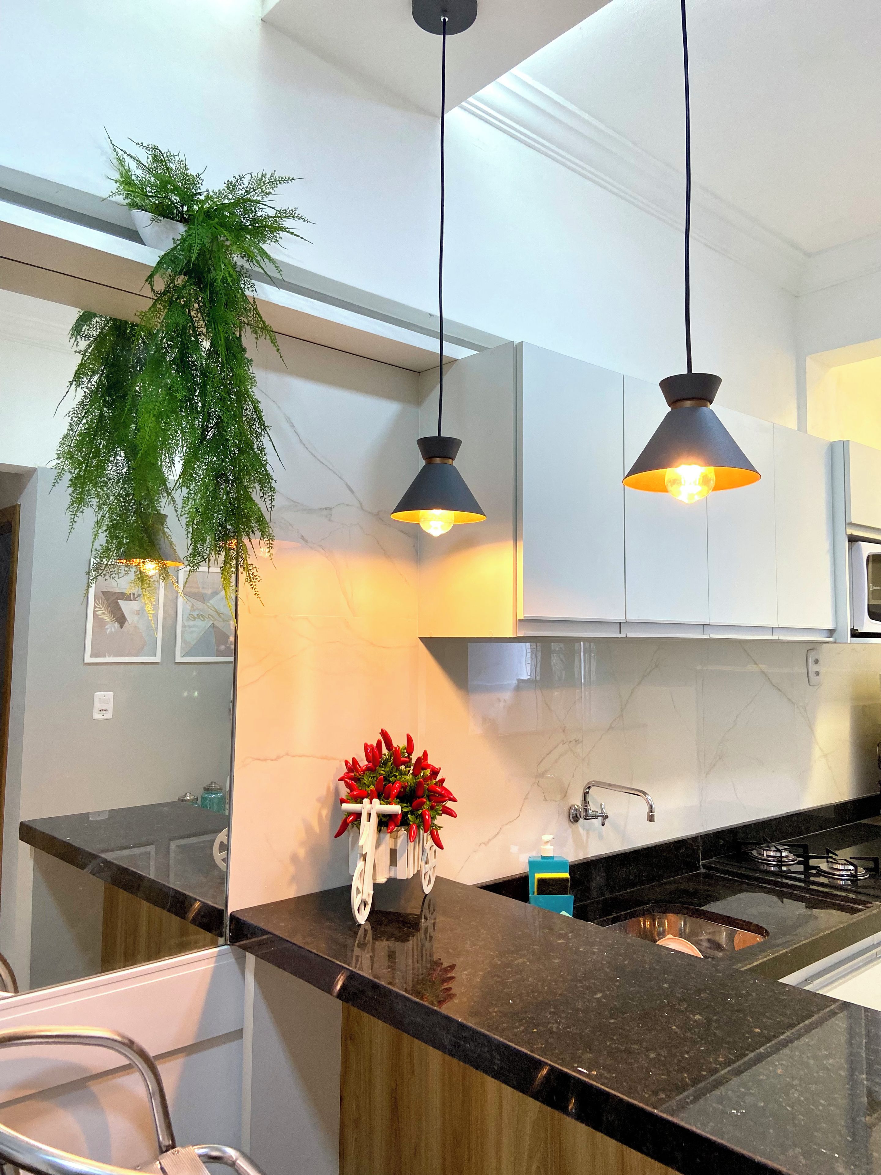 A modern kitchen with black countertops, white cabinets, and two pendant lights.