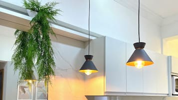 A modern kitchen with black countertops, white cabinets, and two pendant lights.