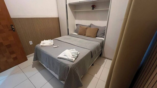 Ein Hotelzimmer mit Bett, Nachttisch, Wandregal und Tür.