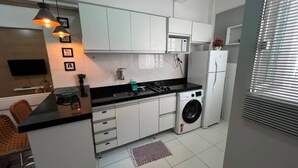 Eine moderne Küche mit weißen Schränken, einer schwarzen Arbeitsplatte, einer Waschmaschine und einer eingebauten Mikrowelle.