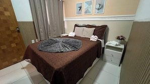 Ein Hotelzimmer mit einem Bett, einem Nachttisch, einem an der Wand befestigten Regal und einer Tür.