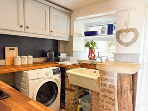 A laundry area with a washing machine, a sink, and a window with a view. - Ruby Cottage | Garden & Wood Burner Near Stamford (Easton on the Hill)