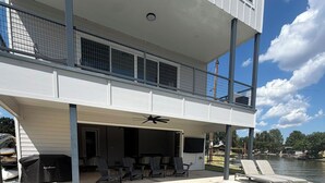 Una piscina con terraza techada, mobiliario exterior y vista a un cuerpo de agua.