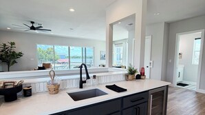 Una cocina moderna con una isla central, armarios oscuros y vistas al exterior.