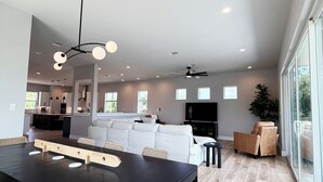 Un espacio habitable amplio con una mesa de comedor, asientos y una cocina al fondo.