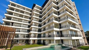 A multi-story hotel with balconies, a swimming pool, and a well-maintained lawn. - Dpto. nuevo a unos pasos de malecón y zona dorada (Mazatlán)