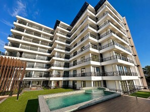 A multi-story hotel with balconies, a swimming pool, and a well-maintained lawn. - Dpto. nuevo a unos pasos de malecón y zona dorada (Mazatlán)