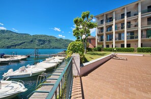 A waterfront hotel with a dock, boats, and a mountainous backdrop. - Domus Lario's Lake – stunning view, beach, swimming pool, and private parking (Lierna)