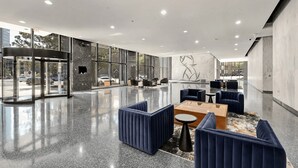 A modern lobby with a glass entrance, seating area, and a marble wall with a geometric design. - Luxury City Escape | King Bed + Rooftop (Birmingham)