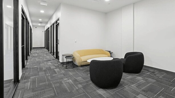 A modern office space with a carpeted floor, a sofa, two round tables, and a row of glass doors. - Luxury City Escape | King Bed + Rooftop (Birmingham)