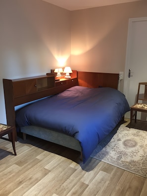 Ein Schlafzimmer mit Bett, Nachttisch, Lampe und Teppich.