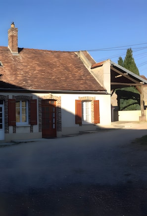 Ein zweigeschossiges Haus mit Backsteinkamin, Ziegeldach und überdachter Veranda.