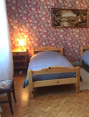 Ein Schlafzimmer mit einem hölzernen Bett, einem Nachttisch mit Lampe, einem Sessel und einem Bild an der Wand.