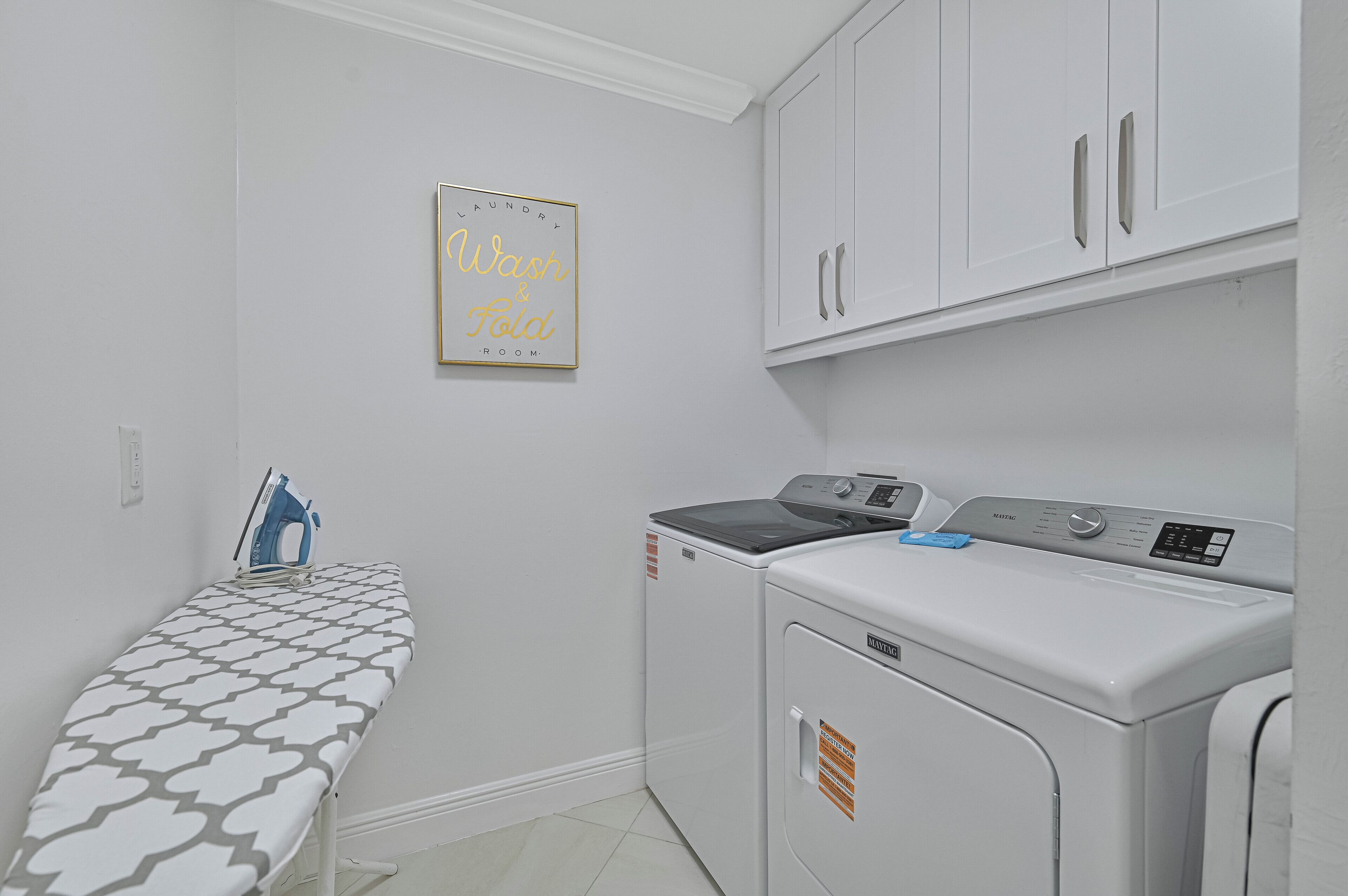 A laundry room with a washing machine, dryer, and ironing board.