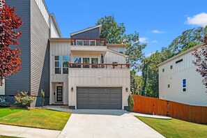 Ein zweistöckiges Haus mit Garage, Balkon und umzäunter Garten.