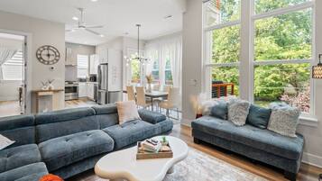 A modern living room with a sectional sofa, a coffee table, and a dining area with a chandelier.
