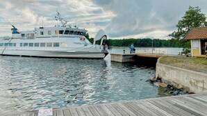A large yacht docked at a pier with a wooden walkway leading to a small building. - Modern house in Staveström, Stockholm Archipelago (Ljusterö)