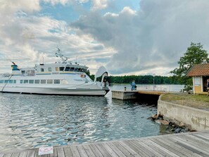 Eine große Yacht liegt an einem Steg, verbunden durch eine Holzpromenade zu einem kleinen Gebäude.