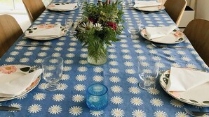 A dining table set for six with a blue floral tablecloth, a vase of flowers, and a painting on the wall. - Modern house in Staveström, Stockholm Archipelago (Ljusterö)