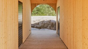 A wooden interior with a balcony, a wooden floor, and a view of a natural landscape. - Modern house in Staveström, Stockholm Archipelago (Ljusterö)