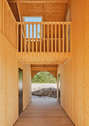 Ein Holzinnenraum mit Balkon, Holzboden und Blick auf eine natürliche Landschaft.