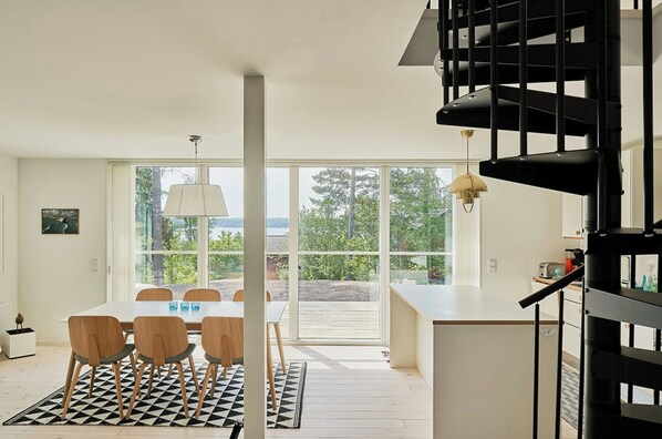 Un intérieur moderne comprenant un coin repas, un escalier et de grandes fenêtres.
