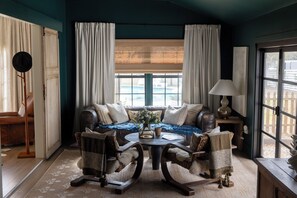 Een gezellige kamer met een bank, twee fauteuils, een salontafel en een raam met gordijnen.