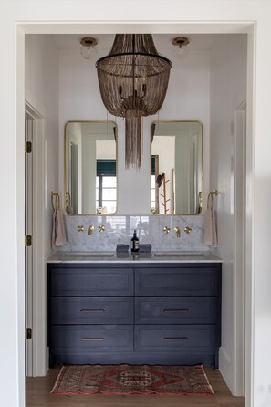 A bathroom with a double vanity, a chandelier, and a large mirror. - Hotel Bebe Main House - Sleeps 6 (Round Top)