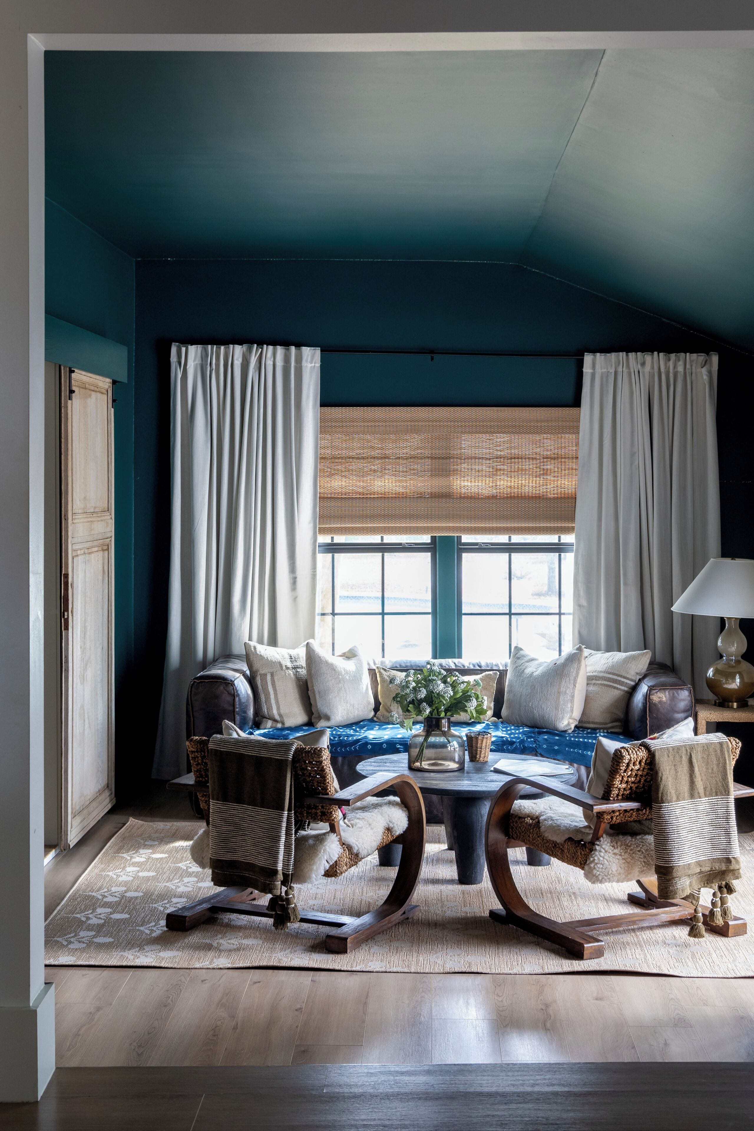 A room with a blue accent wall, a sofa set, a coffee table, and a lamp.