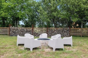 Een terras met witte stoelen en een vuurkorf.